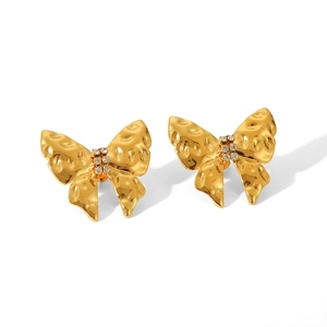 Macro shot of 18K gold plated bow earrings with hammered texture and crystal inlay