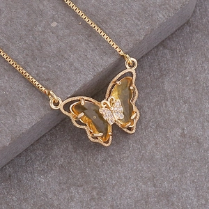 Macro shot of 18K gold butterfly necklace with yellow crystals on stone background