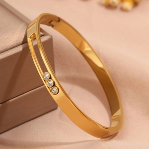Macro shot of polished gold titanium steel bangle with three sliding cubic zirconia diamonds