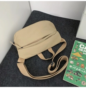 Detailed top view of a khaki crescent nylon crossbody bag on a textured grey background
