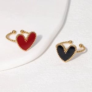 Detail of gold twisted rings with red and black heart enamel on a stone tray