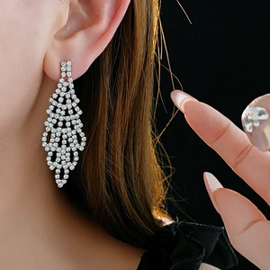Close-up of sparkling silver diamond earrings featuring a floral pave setting on model