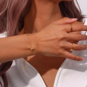 Detail of 18K gold-plated minimalist chain bracelet and diamond rings on model hand