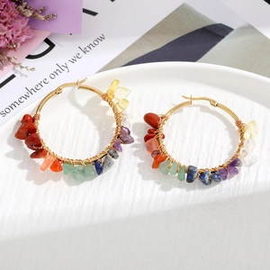 Detail of handmade bohemian hoop earrings with colorful natural stones on gold-tone metal