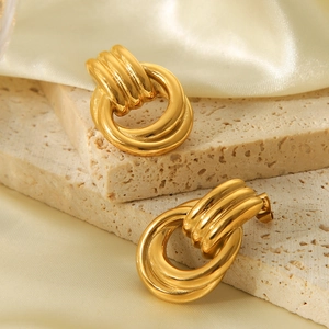 Detailed macro view of 18k gold plated stainless steel twisted hoop earrings on stone
