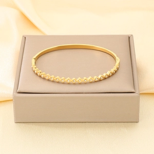 Dettaglio di un elegante bracciale rigido in acciaio dorato 18K con zirconi bianchi