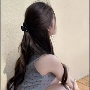 Elegant black matte hair claw clip with white dots worn in a stylish half-up hairstyle