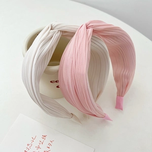 Detail of pleated fabric headbands with elegant knot design in beige and pink tones