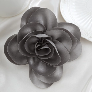 Macro detail of charcoal grey satin rose brooch with realistic layered petal texture