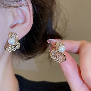 Detail of elegant gold butterfly earrings with pearls and zircon on model's ear