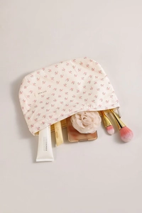 Gros plan d'une trousse fleurie avec fermeture éclair en argent et écusson de marque