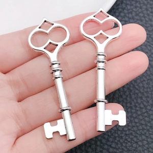 Macro detail of two heart-shaped antique silver key pendants on black leather
