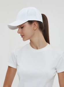Side view of white cotton ponytail baseball cap worn by model in minimalist studio