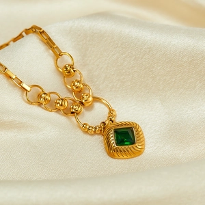 Macro shot of gold square emerald zircon pendant on textured rectangular link chain
