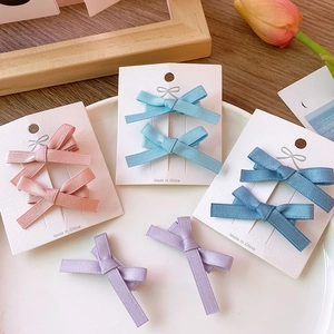 Detail of four colorful ribbon bow hair clips on display card with tulip decoration