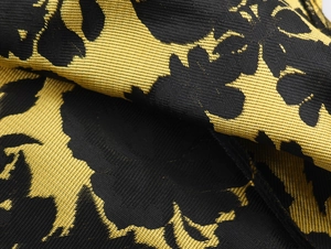 Primer plano de la tela jacquard floral en negro y oro para un vestido vintage sin mangas