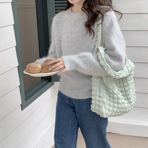 Detail of mint green bubble texture shoulder bag styled with a gray knit sweater