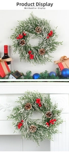 Détail d'une couronne de Noël artificielle avec pommes de pin et baies rouges sur cheminée