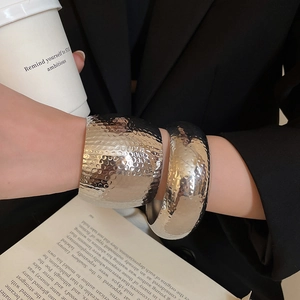 Detail view of silver hammered texture wide bracelets on wrist with casual styling