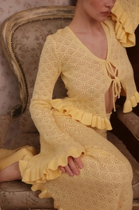Detail of light yellow crochet knit two-piece set with tie-front top and ruffled edges