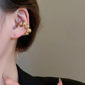 Dettaglio del raffinato ear cuff a sfere dorate per cartilagine senza fori all'orecchio