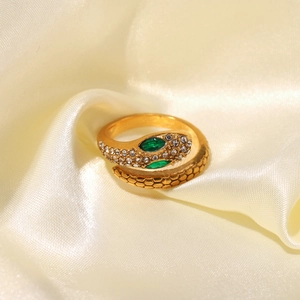 18K gold plated snake ring with green zircon eyes on elegant silk fabric background