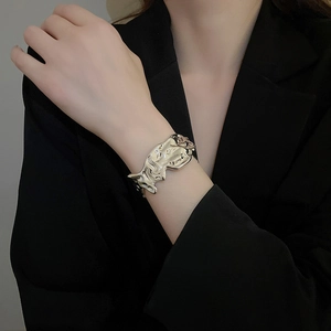 Close-up of irregular silver lava texture open cuff bracelet on a black blazer sleeve