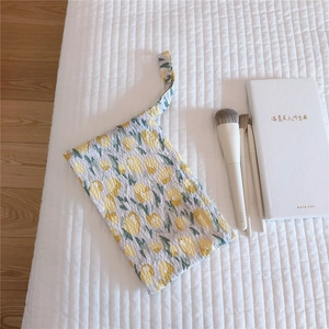 Close-up of yellow floral waffle fabric wristlet bag on a minimalist background