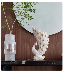 Close-up of white peacock vase with gold accents on marble surface in home setting