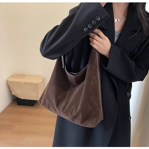 Close-up of a large brown suede tote bag carried by a model in a black blazer