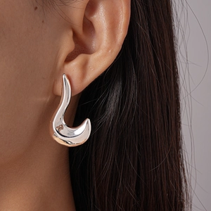 Close-up of sleek irregular geometric silver stud earrings on model for a minimalist look