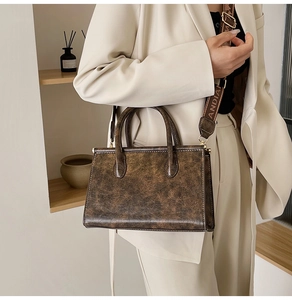 Detail of vintage brown textured tote bag with branded jacquard strap and gold hardware