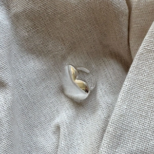 Top view of a minimalist 925 silver heart ring on a beige textured linen background