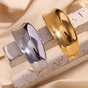 Detailed view of 18K gold and silver polished wave bracelets on a silk fabric background