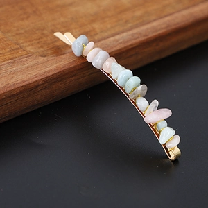 Macro shot of gold metal hair clip with natural colorful crystal stones on wooden tray