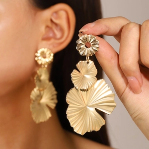 Gros plan sur les boucles d'oreilles feuilles de ginkgo dorées au design vintage chic