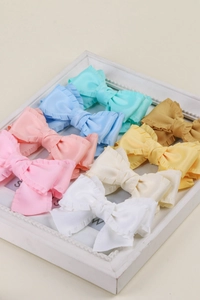 Détail de barrettes nœuds en ruban plissé aux tons pastel dans un cadre rétro