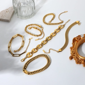 Flat lay of multiple 18K gold plated Cuban and snake chain bracelets with premium props