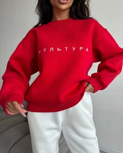 Detail of red crewneck sweatshirt featuring white Cyrillic embroidery and V-stitch collar