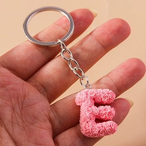 Close-up of pink resin letter E keychain with detailed embossed rose floral patterns
