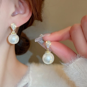 Detailed view of luxury gold earrings with zircon teardrops and large white pearls
