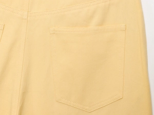 Détail de la poche arrière et des coutures d'un pantalon jaune large en sergé de coton