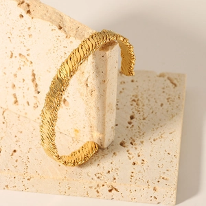 Detailed macro view of the twisted woven texture on a gold open-cuff stainless steel bracelet