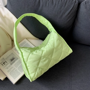Quilted lime green nylon tote bag on a dark grey sofa next to an open magazine