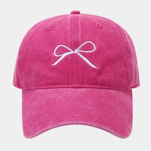 Dettaglio del ricamo a fiocco bianco su cappello da baseball rosa lavato