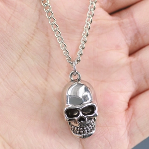 Macro shot of silver skull pendant necklace with twisted chain held in hand