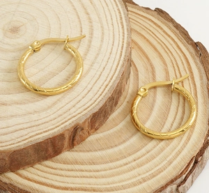 Detail of 18k gold plated hoop earrings with spiral texture on natural wood slabs