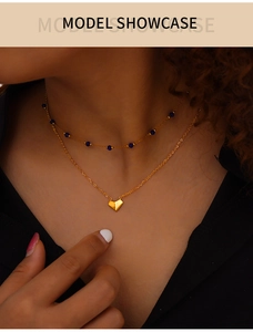 Detail of layered gold titanium necklace with blue beads and geometric heart pendant