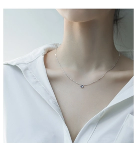 Dettaglio macro della collana in argento S925 con gemma blu tonda sulla clavicola