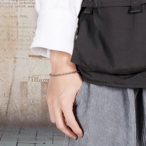 Close-up of minimalist silver stainless steel chain bracelet on a male wrist